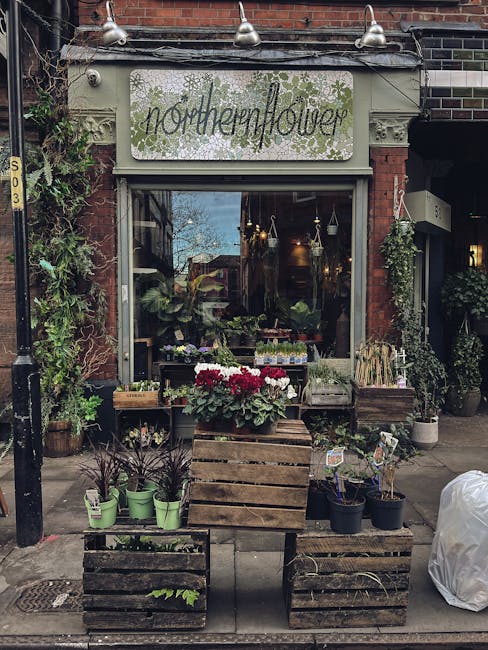 The exterior of Northern Flower, a florist shop on Upper Street Islington, featuring a rustic display of potted plants and flowers arranged on wooden crates outside the shop. The display includes gree
